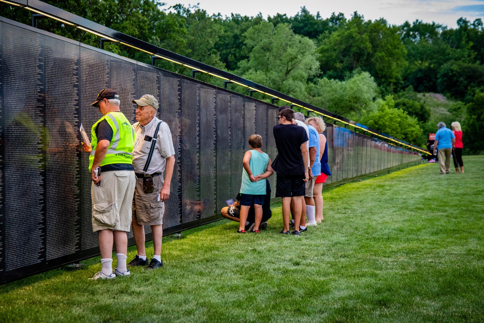 The Wall That Heals being viewed by two elderly gentlemen and another family group out in the park.