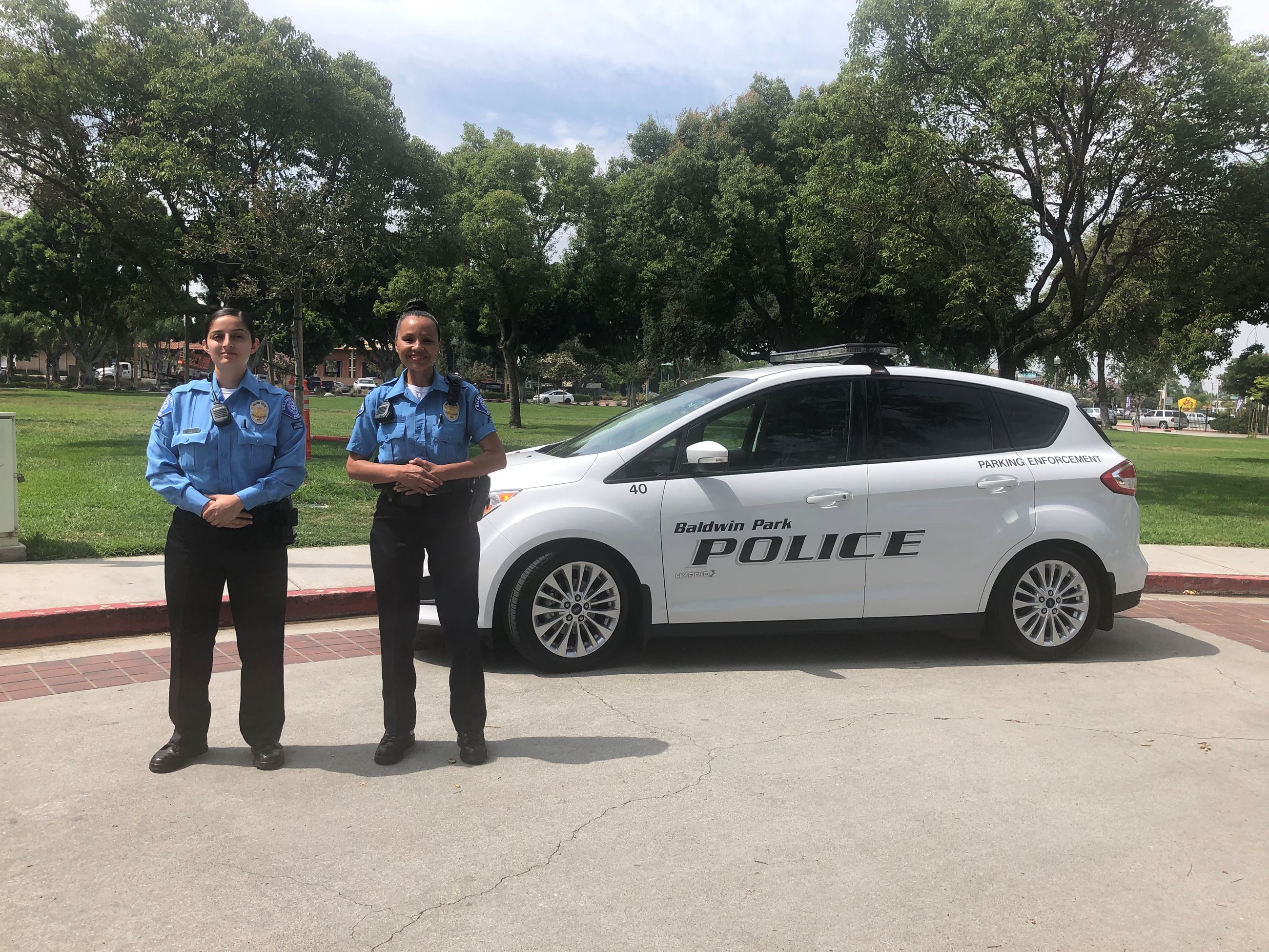 Two cops stand in front of a police car